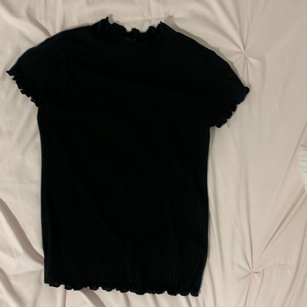 This is a black shirt with ruffles on the neck line and on the shoulders.